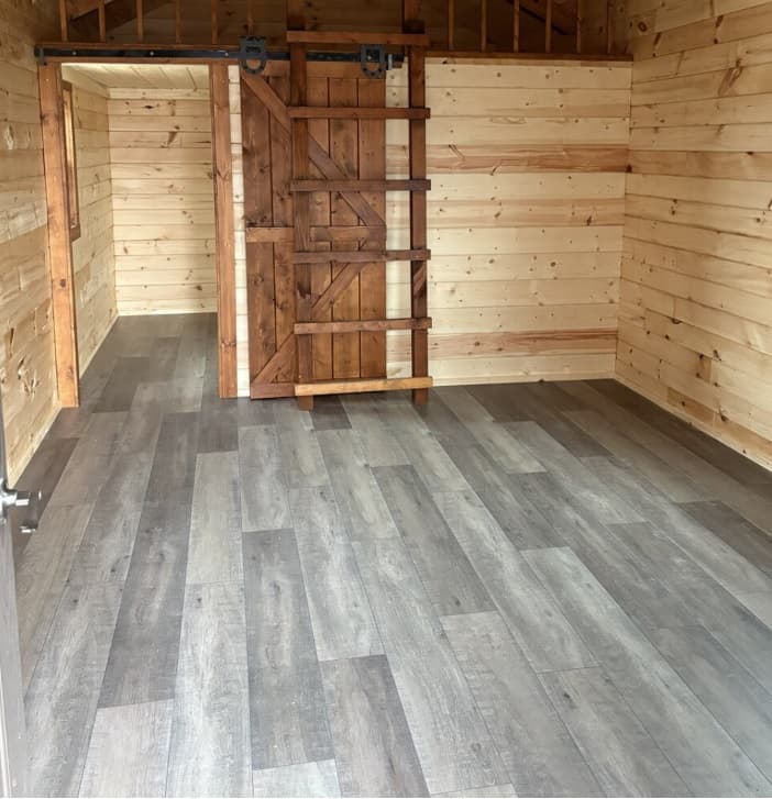 Log cabin interior with rustic sliding barn door and gray laminate flooring