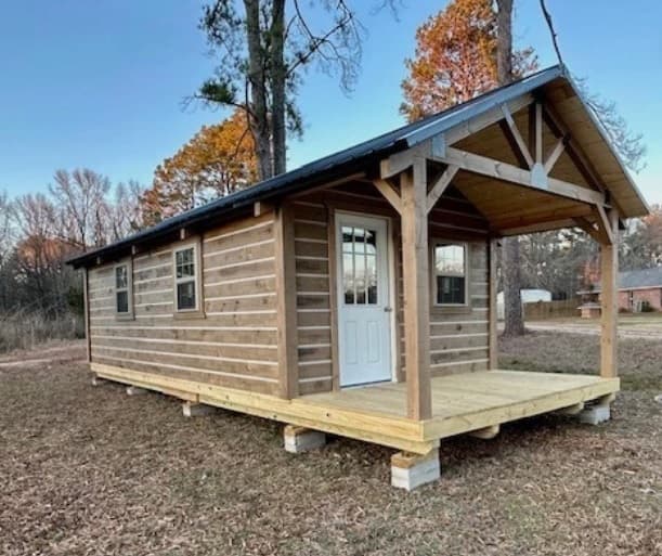 Modern chinked log cabin with covered front porch in autumn